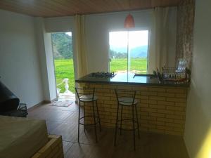 a kitchen with a bar with stools and a window at Loft 1 Sitio Cachoeiras do Caledônia in Nova Friburgo