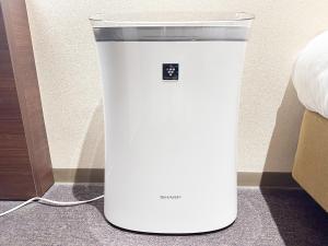 un frigorifero bianco seduto sul pavimento accanto a un letto di Shinsaibashi ARTY Inn ad Osaka