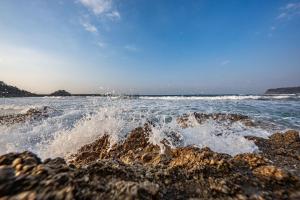 a view of the ocean with waves crashing on the rocks at Free Parking and Sauna INDIGO GEO HOUSE DS2DS3 in Tajiri