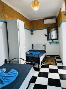 Una habitación con dos camas y suelo de cuadros. en Dar Beldi, en Marrakech 17 fotos más