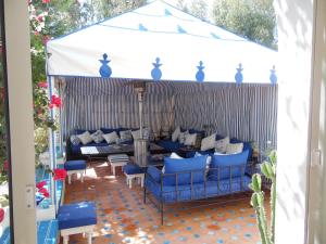d'une terrasse avec des canapés bleus et un auvent blanc. dans l'établissement Villa Daba, à Ghazoua
