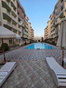 uma piscina com duas cadeiras e um guarda-sol e alguns edifícios em Florenza Khamsin em Hurghada mais 9 fotografias