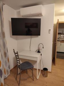 a white desk with a chair and a tv on a wall at Dirnböck & Menneweger in Sankt Josef