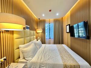 a bedroom with a large bed and a television at Perc Hotel in Pinamungahan