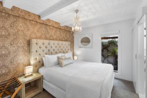a bedroom with a large white bed and a chandelier at Orewa Beachcomber in Orewa