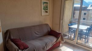 a couch in a living room with a table and a balcony at Signal du Prorel Briançon Serre Chevalier "QOCLICO" in Briançon