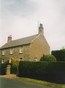 una gran casa de ladrillo con un seto delante de ella en The Old School House Mordington, en Mordington