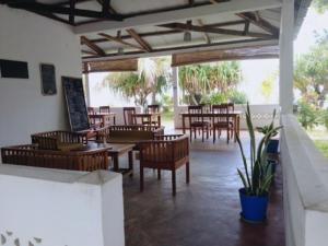 a restaurant with wooden tables and chairs and a patio at Residence Monique in Ile aux Nattes