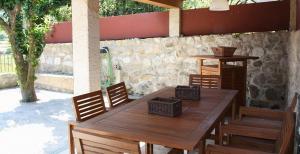 a wooden table and chairs under a stone wall at Casa da Avó in Arcos de Valdevez