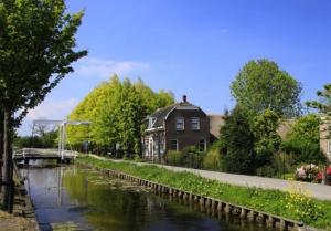 a house next to a river with a building at House of Cocagne in Kockengen