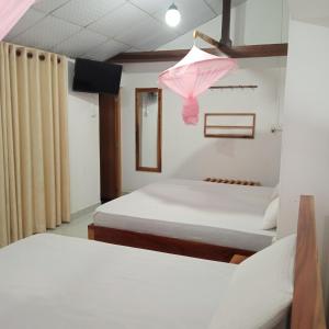 een kamer met twee bedden en een roze paraplu bij 1907 Park View in Anuradhapura