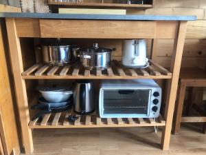 a kitchen shelf with pots and pans and a microwave at La Roulotte d'Alcas in Saint-Jean-et-Saint-Paul +5 photos