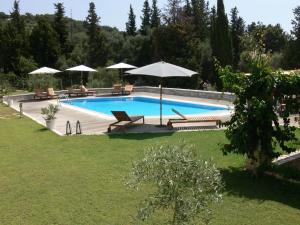a swimming pool with benches and umbrellas in a yard at Alkyon Villas in Syvota