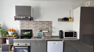 a kitchen with a counter with a microwave and a sink at La belle escale landaise - PDJ inclus, parking, gare & proche Hossegor in Saint-Vincent-de-Tyrosse +6 photos