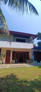 a house with a palm tree in front of it at 'Kolamba Gedara' green apartment in Ruwanwella