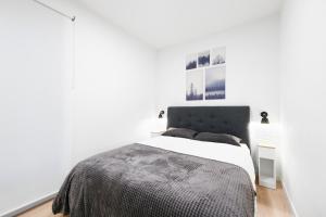 a white bedroom with a bed with a black headboard at Apartamento Posidonia in Canfranc-Estación