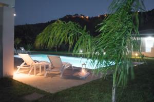 two chairs and a table next to a pool at night at Casa di Varco in Lefkada