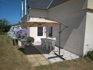 a table with an umbrella on the side of a house at Gîte Ty an Aod - 3 étoiles in Plougrescant