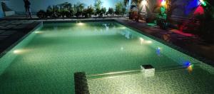 a swimming pool with green water at night at ecr resorts- pleasant stay farmhouse in Sadras +8 photos