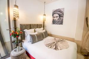 Riad Dar 73 في مراكش: غرفة نوم بسرير أبيض مع صورة على الحائط