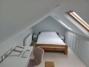 a small attic bedroom with a bed and a desk at Countryside Retreat with Hot Tub in Haselbury Plucknett