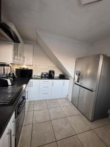 Una cocina con gabinetes blancos y un refrigerador de acero inoxidable. en Jarman house, London, en Londres