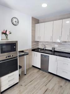 een keuken met witte kasten en een klok aan de muur bij Casa del Tío Paco in Montecorto