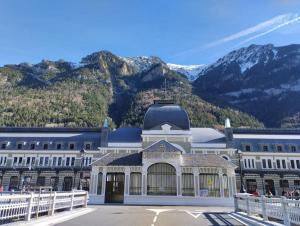 a large white building with mountains in the background at Apartamento Posidonia in Canfranc-Estación