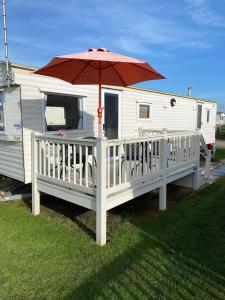 a white rv with a porch with an umbrella at 6 Berth Caravan - Heacham Holiday Park in Heacham
