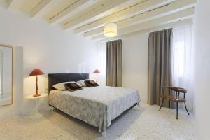 a white bedroom with a bed and a chair at Mia Casa in Venice