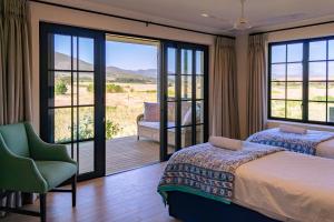 a bedroom with a bed and a balcony with a view at Klein River Cottage, Stanford Getaway in Stanford +32 photos