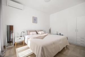 a white bedroom with a bed and a television at Blue Horizon Apartment a Seaside Escape in Rabac in Rabac