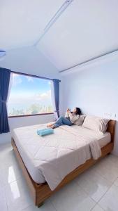 a man laying on a bed in a room with a window at Pondok Alengkong in Bangli