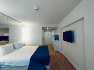 Un dormitorio con una gran cama blanca y un televisor. en Amazing Holiday Orbi Aparthotel, en Batumi