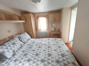 a bedroom with a bed with a checkered bedspread at D21 Kirbys Retreat 1, skegness in Winthorpe