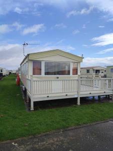 a white house with a porch on the grass at D21 Kirbys Retreat 1, skegness in Winthorpe