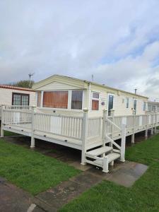 a white mobile home with a porch and a fence at D21 Kirbys Retreat 1, skegness in Winthorpe
