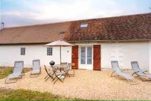 a patio with chairs and a table and an umbrella at Jolie maison cosy en sologne in Romorantin