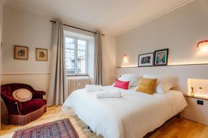 een slaapkamer met een groot wit bed en een stoel bij Le Falcoz in Saint-Jean-de-Maurienne