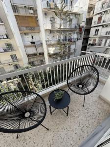 two chairs and a table on a balcony with buildings at Hidden Gem Apartment in Patra