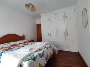 a white bedroom with a bed and a mirror at Unmei in Lagoa