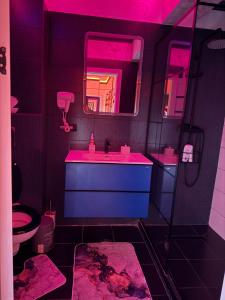 a purple bathroom with a sink and a mirror at Relax Regim Apartament in Bucharest
