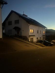 a white house with a car parked in front of it at Ferienwohnung Schieferglück in Gründau