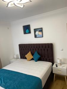 a bedroom with a large bed with blue and yellow pillows at Апартамент Дани in Obzor