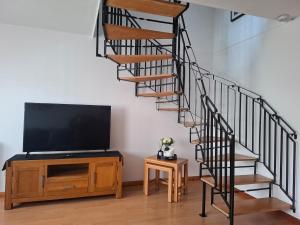 a living room with a tv and a spiral staircase at Cosy Manorfield Holiday Home in Kent