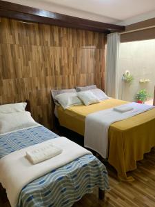 two beds in a room with wooden walls at Pousada Elizondo in Natal +6 photos