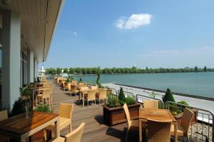 a row of tables and chairs on a deck next to the water at Courtyard by Marriott Hannover Maschsee in Hannover