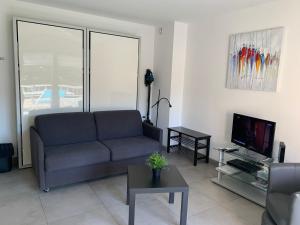 ein Wohnzimmer mit Sofa und Fernseher in der Unterkunft Beau Studio climatisé, parking privé Sanary centre in Sanary-sur-Mer + 11 Fotos