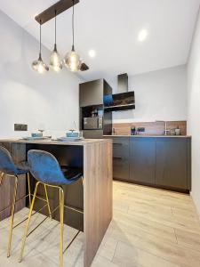 a kitchen with a counter and some blue chairs at L'Escapade - Love room & spa in Haguenau