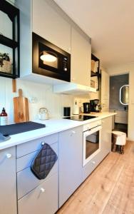 a kitchen with white cabinets and a stove top oven at Leilighet midt i Sokndal sentrum in Sokndal